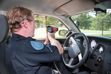 A policeman using a radar gun. A policeman using a radar gun.