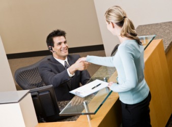 A receptionist greets a businesswoman. A receptionist greets a businesswoman.