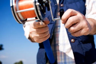 A man uses a fishing reel. A man uses a fishing reel.