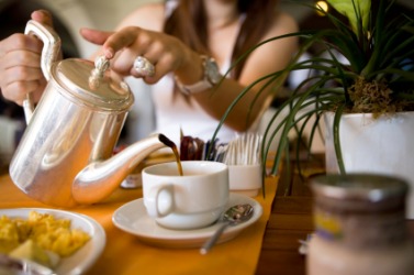 A woman pours tea at teatime. A woman pours tea at teatime.
