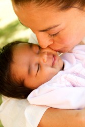 A mother tenderly kisses her baby. A mother tenderly kisses her baby.