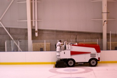 A zamboni being used on an ice rink. A zamboni being used on an ice rink.