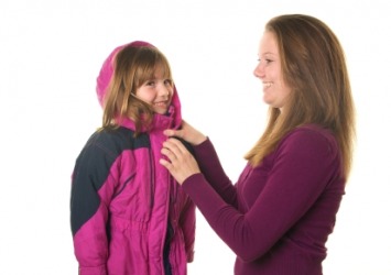 A mother fastens her daughters coat. A mother fastens her daughters coat.