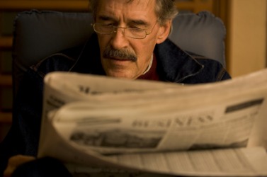 A man reading a gazette. A man reading a gazette.