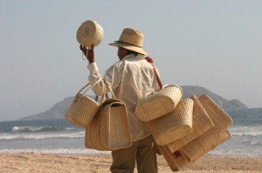 A man peddles baskets on the beach. A man peddles baskets on the beach.