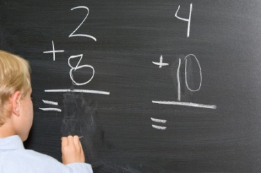 A child does addition problems on the blackboard. A child does addition problems on the blackboard.