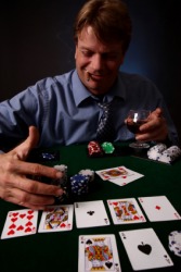 A man taking his winnings from a bet he placed in a card game. A man taking his winnings from a bet he placed in a card game.