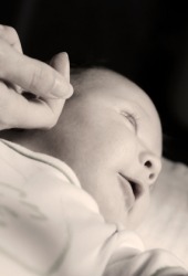 A mother strokes her baby's cheek with tenderness. A mother strokes her baby's cheek with tenderness.