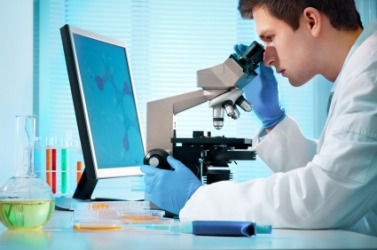 A scientist examines something under a microscope. A scientist examines something under a microscope.
