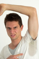 A man dismayed by the perspiration stains under his arm. A man dismayed by the perspiration stains under his arm.