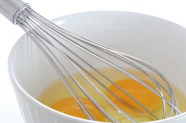 A whisk in a bowl of eggs. A whisk in a bowl of eggs.