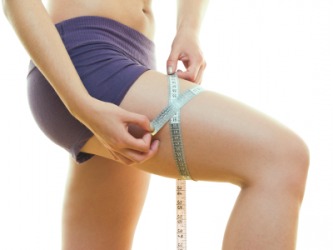 A woman measuring her thigh. A woman measuring her thigh.