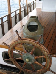 A ships wheel with brass binnacle behind it. A ships wheel with brass binnacle behind it.
