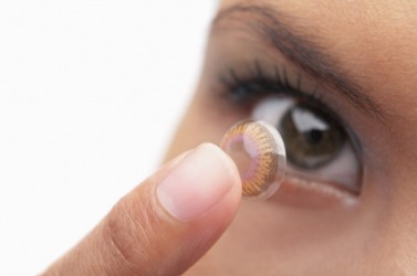 A woman about to place a contact lens on her eye. A woman about to place a contact lens on her eye.
