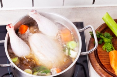 A chicken simmers in a pot. A chicken simmers in a pot.