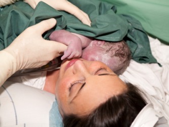 A woman holding her baby just after giving birth. A woman holding her baby just after giving birth.