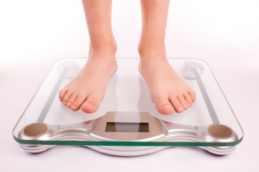 A woman steps on the scale to ascertain her weight. A woman steps on the scale to ascertain her weight.