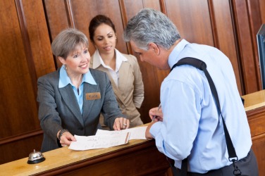 A hotel guest signs the register. A hotel guest signs the register.
