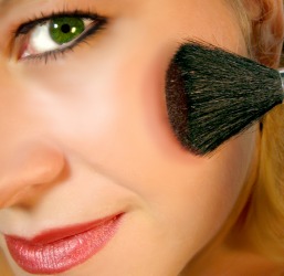 A woman applies rouge to her cheeks. A woman applies rouge to her cheeks.