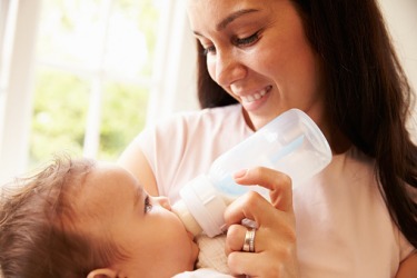 A mother pacifying a baby with a bottle. A mother pacifying a baby with a bottle.