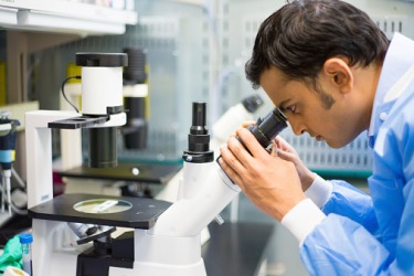 A scientist looking through a microscope. A scientist looking through a microscope.