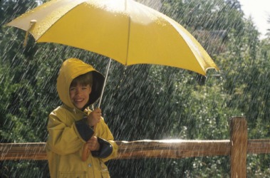 A boy with an umbrella standing in the pelting rain. A boy with an umbrella standing in the pelting rain.
