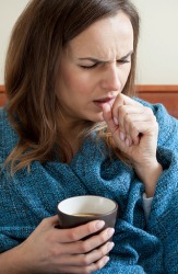 A sick woman drinking hot tea to calm her cough and loosen phlegm. A sick woman drinking hot tea to calm her cough and loosen phlegm.
