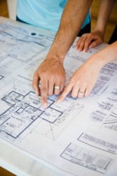 Couple pointing to blueprints Couple pointing to blueprints
