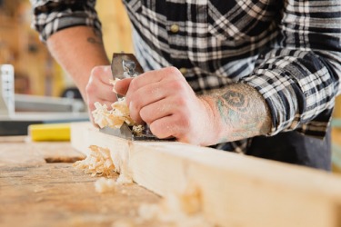 A woodworker planing a piece of wood. A woodworker planing a piece of wood.