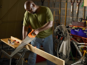 A man cutting a plank of wood with a saw. A man cutting a plank of wood with a saw.