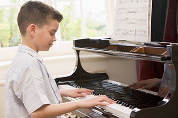 A young boy practising playing the piano. A young boy practising playing the piano.