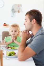 A father and daughter giving thanks before eating their meal. A father and daughter giving thanks before eating their meal.