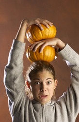 A girl balancing two pumpkins precariously on her head. A girl balancing two pumpkins precariously on her head.