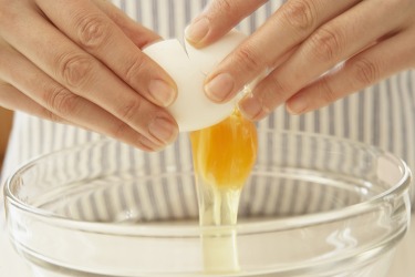Breaking an egg into a bowl Breaking an egg into a bowl