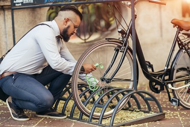 Owen reeves the lock through the bar to safely secure his bicycle while he is at work all day. Owen reeves the lock through the bar to safely secure his bicycle while he is at work all day.