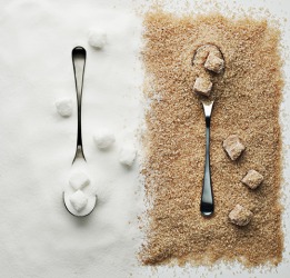 The refined white sugar is on the left, whereas the raw sugar on the right has a tan color. The refined white sugar is on the left, whereas the raw sugar on the right has a tan color.