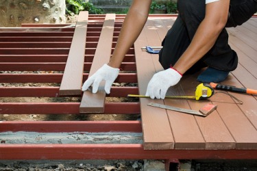 The handyman is planking the back deck of the house. The handyman is planking the back deck of the house.