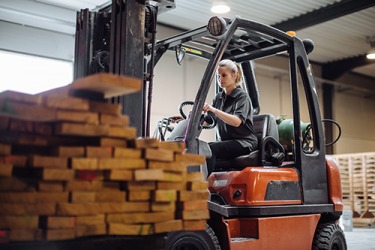 Theresa shifted the forklift into reverse after loading up the stack of wood. Theresa shifted the forklift into reverse after loading up the stack of wood.