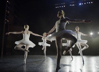 The ballet dancers revolve in unison while pirouetting during their performance on stage. The ballet dancers revolve in unison while pirouetting during their performance on stage.