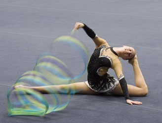 The rhythmic gymnast twirls a ribbon to enhance her artistic routine. The rhythmic gymnast twirls a ribbon to enhance her artistic routine.