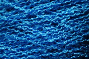 A close up of blue bouclé yarn. A close up of blue bouclé yarn.