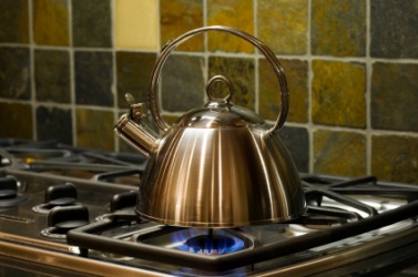 A kettle sitting on the lite burner of a gas stove. A kettle sitting on the lite burner of a gas stove.