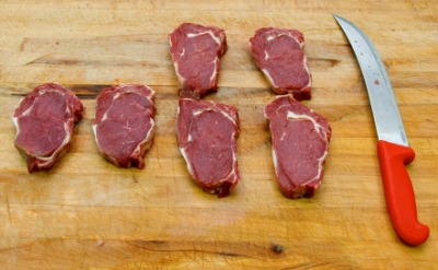 Steaks and a knife on a butcher block. Steaks and a knife on a butcher block.