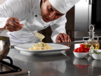 A chef putting the finishing touches on a plate of pasta. A chef putting the finishing touches on a plate of pasta.