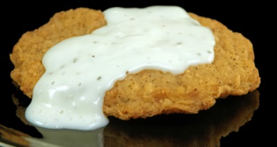 A piece of chicken-fried steak with gravy. A piece of chicken-fried steak with gravy.