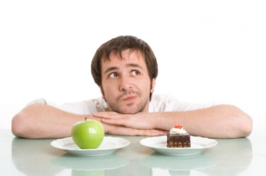 A man trying to make the choice between an apple or a dessert. A man trying to make the choice between an apple or a dessert.