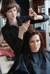 A woman having her hair cut by a coiffeuse. A woman having her hair cut by a coiffeuse.