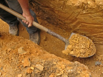 A man using a spade to dig a trench. A man using a spade to dig a trench.