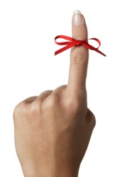 A womans hand with a red ribbon tied around one digit. A womans hand with a red ribbon tied around one digit.