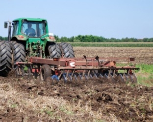 A disk harrow being pulled by a tractor. A disk harrow being pulled by a tractor.